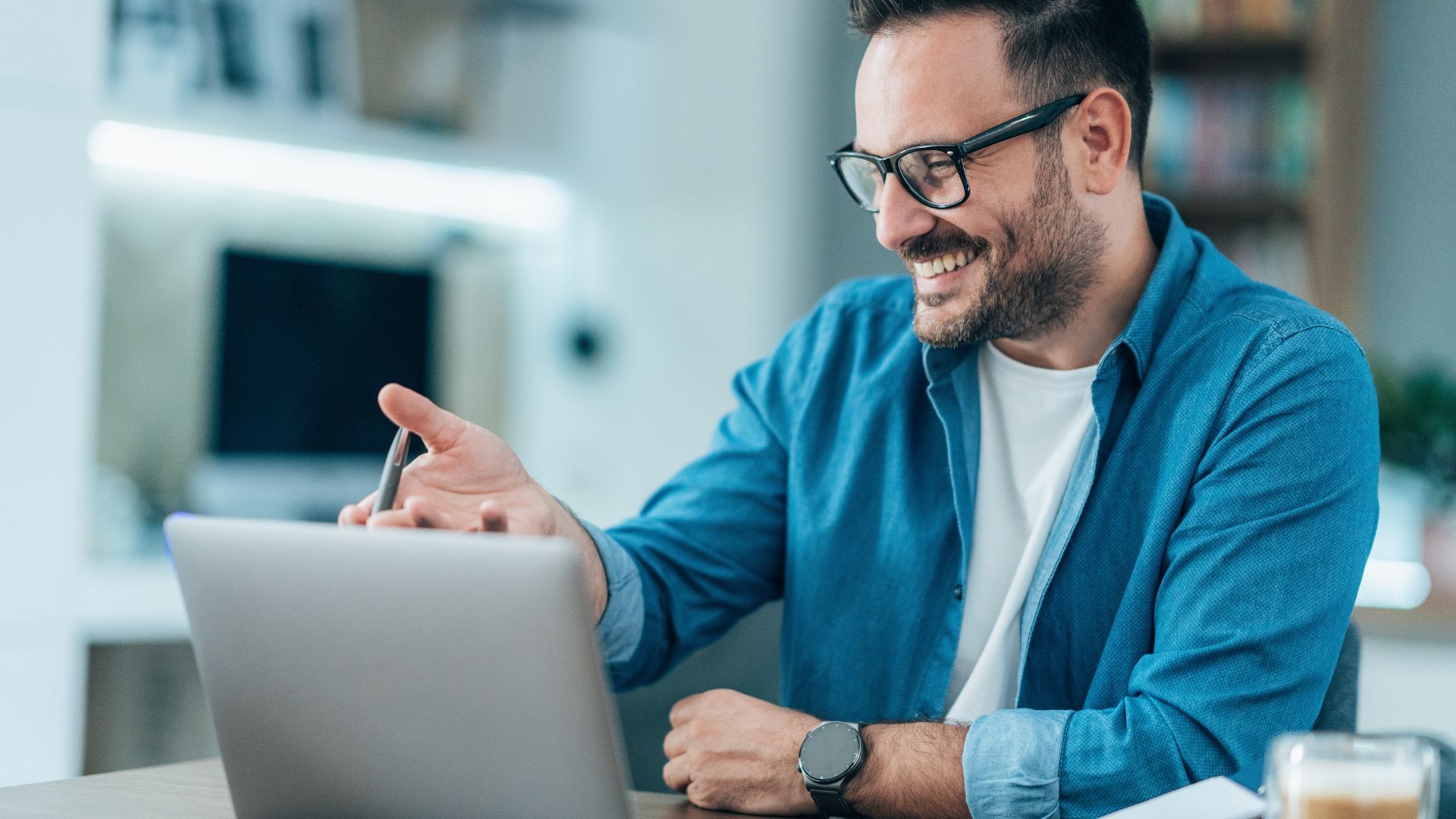 - Professional man working on laptop
- Smiling individual in office setting
- Modern office background with computer and furniture