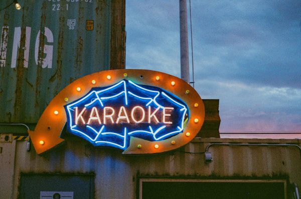 Karaoke neon sign, entertainment venue, nightlife, social gathering, musical activity, city atmosphere, illuminated sign, commercial sign