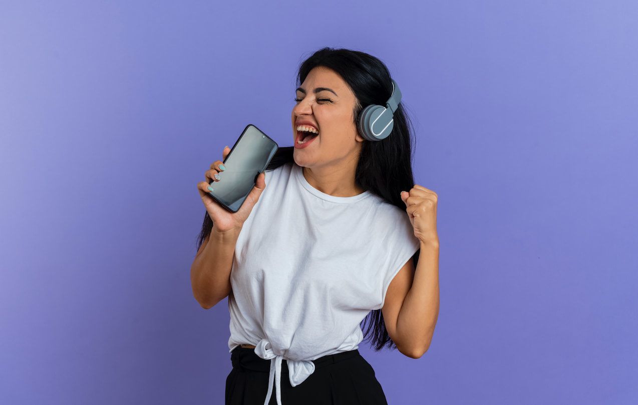 Young woman enjoying music on smartphone with headphones, purple background, modern lifestyle, karaoke apps, mobile entertainment, singing experience